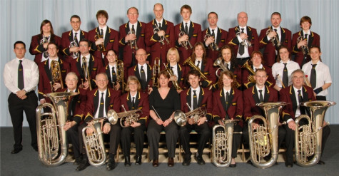 A band holding different brass instruments, sitting down together