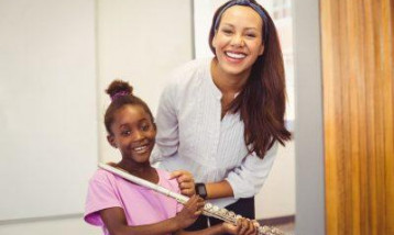 One girl with her flute teacher, both looking happy.